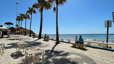a group of people sitting on benches near the beach at Noly by Check-in Portugal in Albufeira