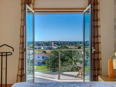 a bedroom with a large glass door that opens to a balcony at Holiday Home Encosta dos Salgados by Interhome in Galé