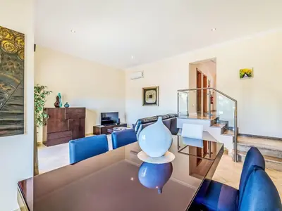 a living room with a glass table and blue chairs at Holiday Home Encosta dos Salgados by Interhome in Galé