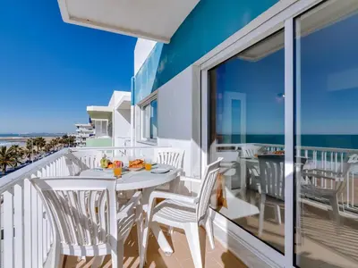 a balcony with a table and chairs and the ocean at AL - Apartamento Canto do Mar frente à praia in Quarteira