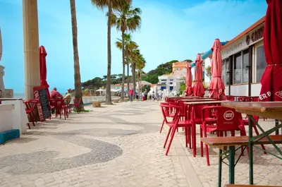 a row of red tables and chairs with palm trees at Varandas do Mar, Olhos de Agua, 1 Bed Apt AT23 in Olhos de Água