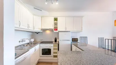 a kitchen with white cabinets and a counter top at Balaia Project by LovelyStay in Olhos de Água