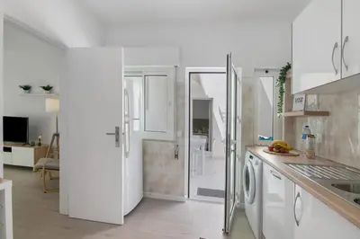 a white kitchen with a washer and dryer at Refúgio Estrela do Mar in Quarteira