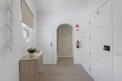 a hallway with white walls and a door with a potted plant at Refúgio Estrela do Mar in Quarteira