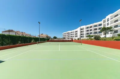 a tennis court in front of a building at Vista das Ondas 208 by JS in Olhos de Água