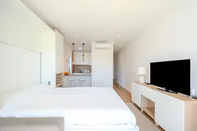 a white bedroom with a bed and a flat screen tv at Galé Beach Studio - Albufeira - Sea View in Guia