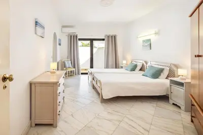 a hotel room with two beds and a television at Villa Coral by OCvillas in Albufeira