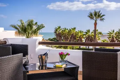 a table with flowers on a balcony with the ocean at Villa Coral by OCvillas in Albufeira