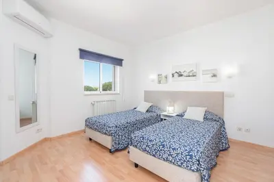 a white bedroom with a bed and two pictures on the wall at Casa da Praia by OCvillas in Albufeira