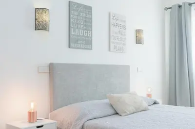 two beds in a room with white walls and wood floors at Casa da Praia by OCvillas in Albufeira