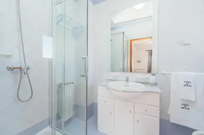 a white bedroom with a bed and a window at Casa da Praia by OCvillas in Albufeira