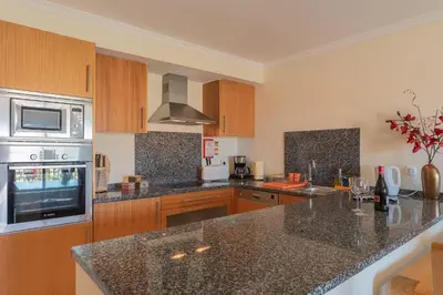 a kitchen with granite counter tops and wooden cabinets at Vista das ondas 205 by AS in Olhos de Água