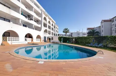 a swimming pool in front of a building at Alta Oura in Albufeira