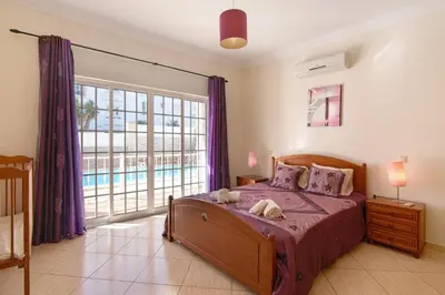 a bedroom with a bed and a large window at Solar das Andorinhas in Albufeira