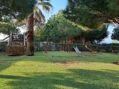 a playground in a yard with a palm tree at Oasis Apartment in Albufeira