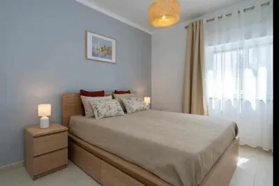a bedroom with a large bed and a window at Mello Apartamento renovado, praia de Quarteira in Quarteira