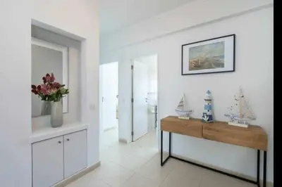 a living room with a table and a vase of flowers at Mello Apartamento renovado, praia de Quarteira in Quarteira