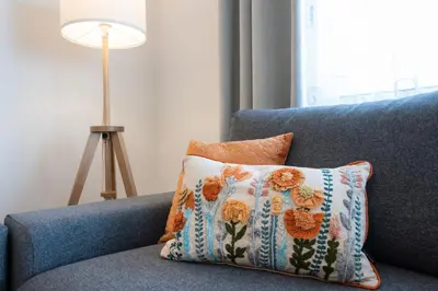 a pillow on a blue couch with a lamp at Mello Apartamento renovado, praia de Quarteira in Quarteira