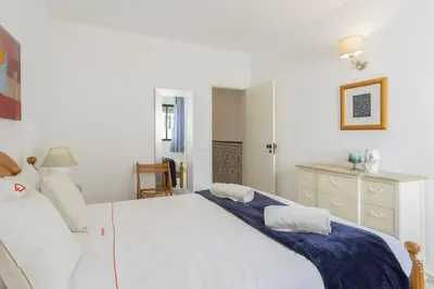 a bedroom with a large white bed and a dresser at Areias de São João 2BR Apartment - Shared Pool & Terrace, by Hopstays in Albufeira