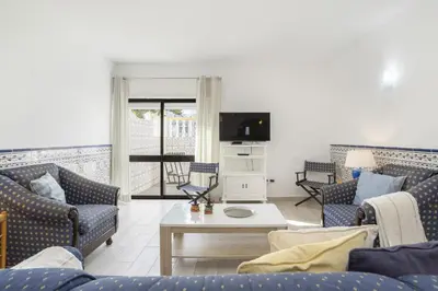a living room with couches and a table and a tv at Areias de São João 2BR Apartment - Shared Pool & Terrace, by Hopstays in Albufeira