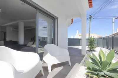 a patio with white chairs and plants on a balcony at Villa Soares - Centro Albufeira - For Families - BY BEDZY in Albufeira