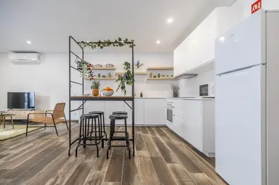a kitchen with white cabinets and a table with stools at Roots Apartments in Faro