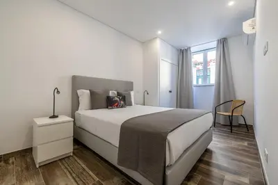 a white bedroom with a bed and a window at Roots Apartments in Faro