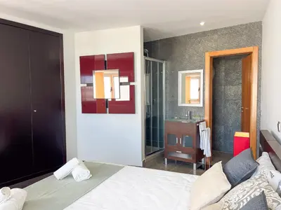 a bedroom with a large bed and a bathroom at Luxury 4-Suite Villa, Pool, Jacuzzi, Games Room in Albufeira