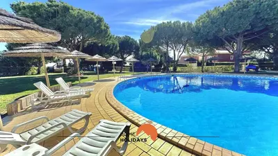 a large swimming pool with chairs and an umbrella at #270 T2 Bicos Flat S by Home Holidays in Albufeira