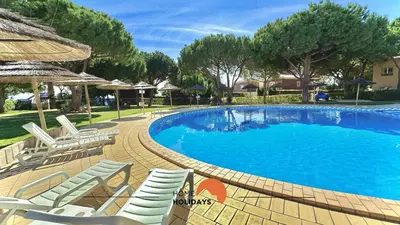 a large swimming pool with chairs and umbrellas at #270 T2 Bicos Flat S by Home Holidays in Albufeira