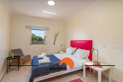a bedroom with a large bed with a red headboard at #270 T2 Bicos Flat S by Home Holidays in Albufeira