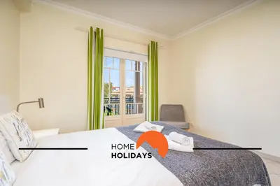 a bedroom with a bed and a window with green curtains at #271 T2 Bicos Flat U by Home Holidays in Albufeira