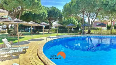 a swimming pool with two chairs and umbrellas at #271 T2 Bicos Flat U by Home Holidays in Albufeira