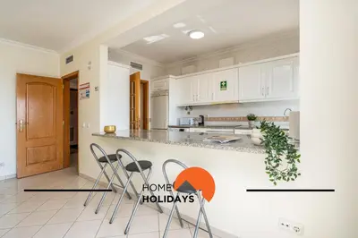 a kitchen with white cabinets and a counter with stools at #271 T2 Bicos Flat U by Home Holidays in Albufeira