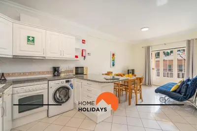 a kitchen with white cabinets and a dining room with a table at #273 T2 Bicos Flat M by Home Holidays in Albufeira