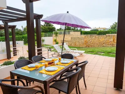 a table with chairs and an umbrella on a patio at Sunshine House by Stay ici Algarve Holiday Rental in Albufeira