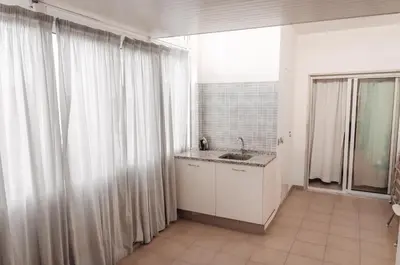 a kitchen with white curtains and a sink and a window at Sea Blue - Frente ao Mar in Quarteira