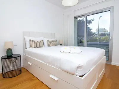 a white bedroom with a large white bed with a window at Green 3 Apartment by Stay ici Algarve Holiday Rental in Albufeira