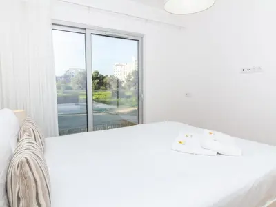 a white bedroom with a white bed and a window at Green 3 Apartment by Stay ici Algarve Holiday Rental in Albufeira