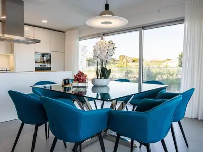 a dining room with a glass table and blue chairs at Green 3 Apartment by Stay ici Algarve Holiday Rental in Albufeira