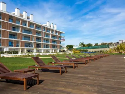 a row of wooden benches in front of a building at Green 3 Apartment by Stay ici Algarve Holiday Rental in Albufeira