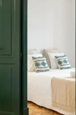 a white bed with blue and white pillows on it at Casa Dona Vitória in Faro