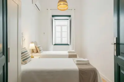 two beds in a white room with a window at Casa Dona Vitória in Faro