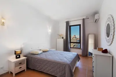 a bedroom with a bed and a mirror on the wall at Oura Beach Cozy Apartment in Albufeira
