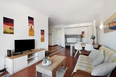 a living room with a couch and a television at Oura Beach Cozy Apartment in Albufeira