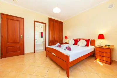 a bedroom with a bed with white sheets and red pillows at Villa Saona by Algarve Vacation in Albufeira