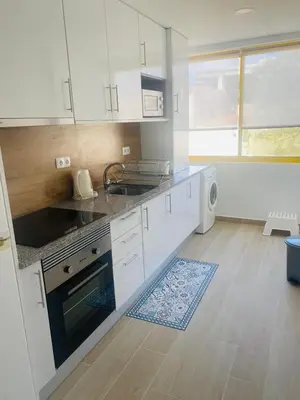 a kitchen with white cabinets and a sink at Apartamento relaxante com terraço e próximo da praia, no 2º andar in Quarteira