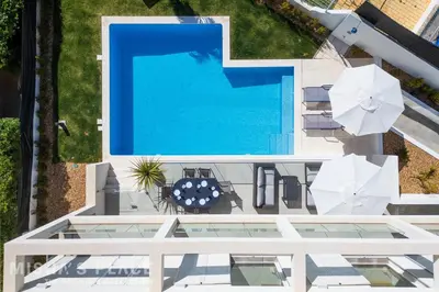 a bedroom with a large bed and two chairs at Villa Alba - Albufeira Premium by Misha's Place in Albufeira