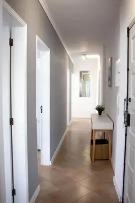 a hallway with white walls and a table and a door at Quarteira-Your Seaside Getaway in Quarteira