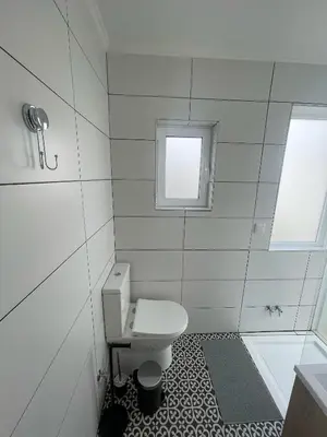 a white bathroom with a toilet and a window at Casa da Baixa in Faro